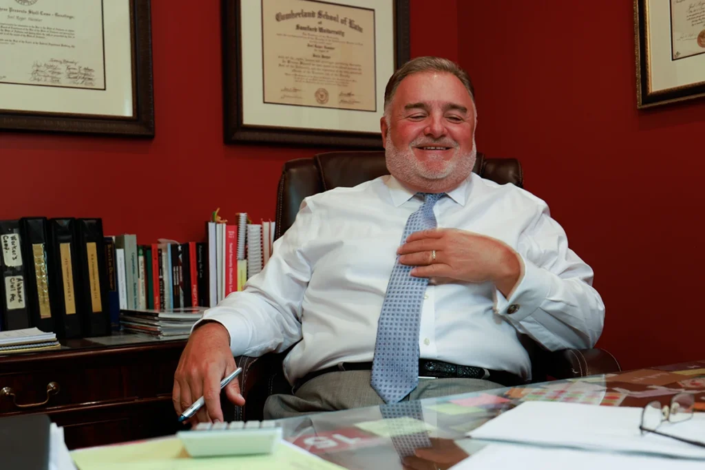 Lawyer Joel Hamner sits in his office, reviewing a car accident exhibit and discussing traffic camera evidence with a client.