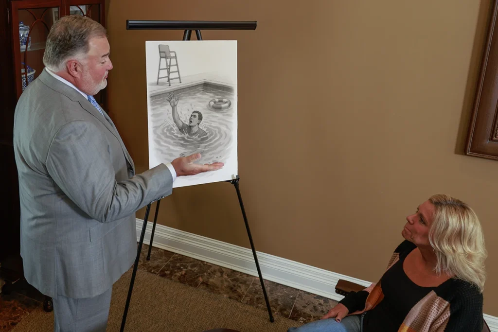 Attorney joel hamner discusses a drowning accident exhibit with a client, covering pool safety failures.