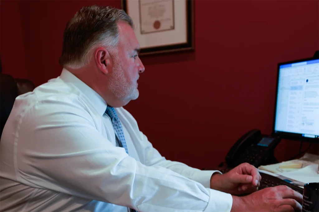 Attorney joel hamner presents a whiplash and neck injury exhibit to a client, showing accident scene diagrams.