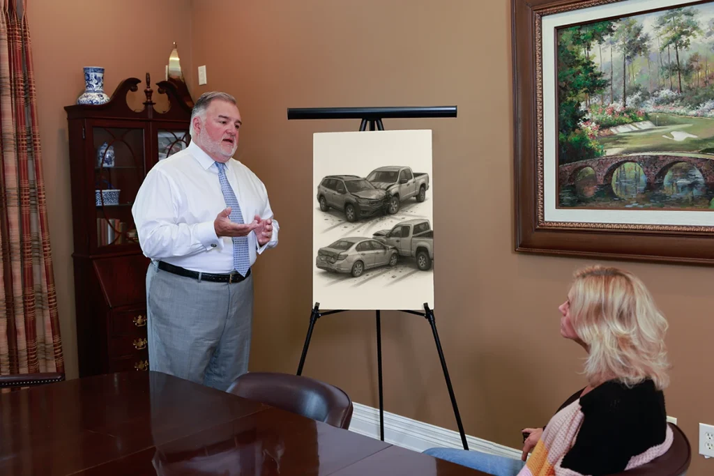 Attorney joel hamner reviews a multiple vehicle collision exhibit with a client, tracing chain reaction impacts.
