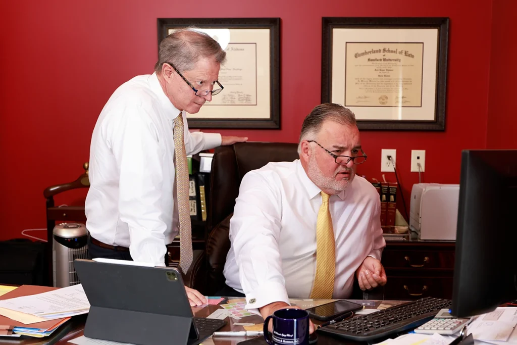 Attorneys tom mccutcheon and joel hamner sit with a client reviewing medical records for a potential amputation injury claim.