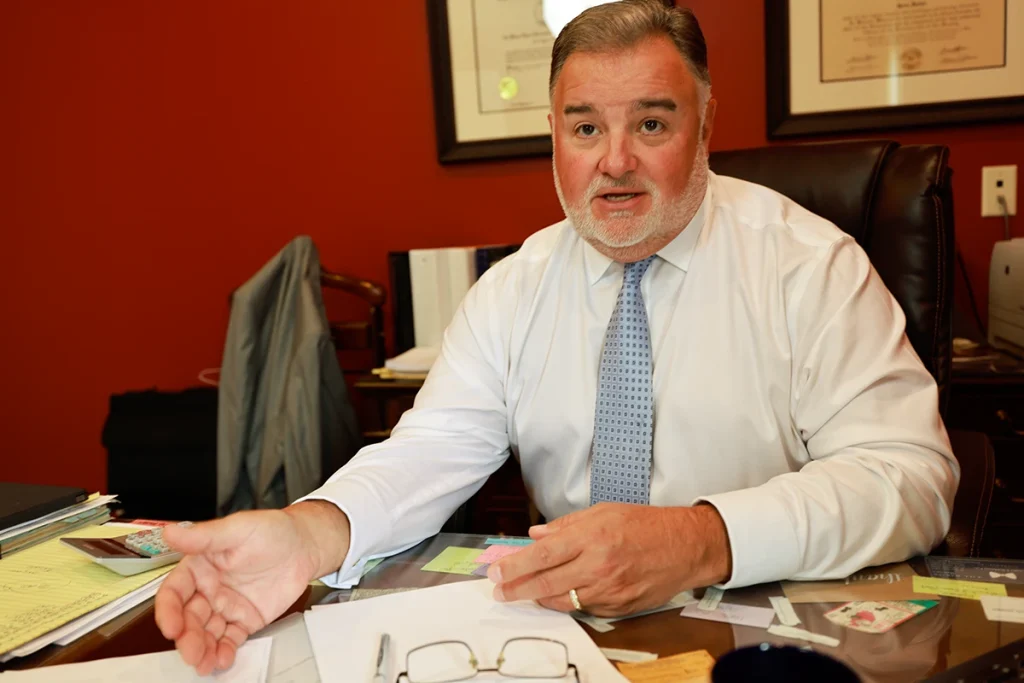 Lawyer joel hamner explains an automotive defects exhibit to a client, outlining recalled parts and inspection findings.