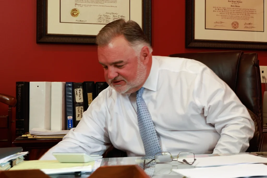 Lawyer joel hamner meets with a client to review a workplace accident exhibit showing safety procedure failures.