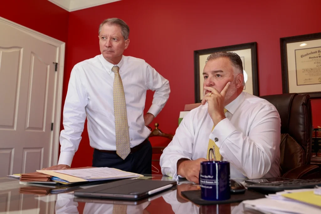 Tom and Joel listen intently during a client consultation in their office, surrounded by legal documents.