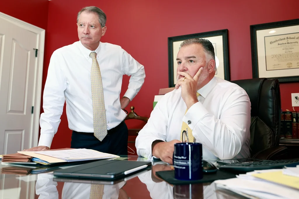 Tom mccutcheon and joel hamner talk with a client regarding compensation for painful joint injuries.
